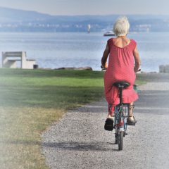 elderly woman riding bicycle near lake